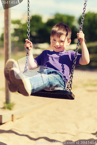 Image of happy little boy swinging on swing at playground