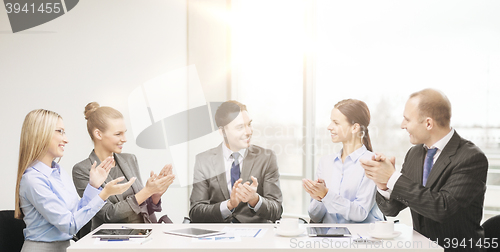 Image of business team with laptop clapping hands