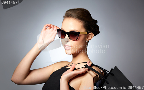 Image of happy woman in black sunglasses with shopping bags