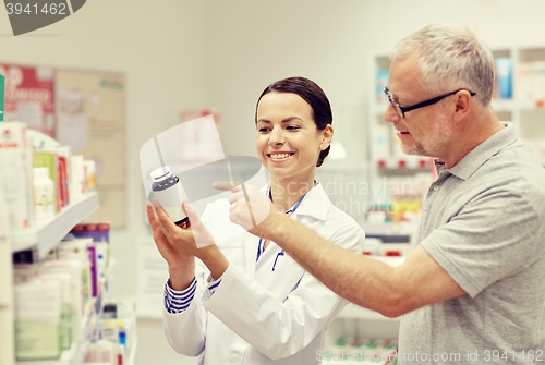 Image of pharmacist showing drug to senior man at pharmacy