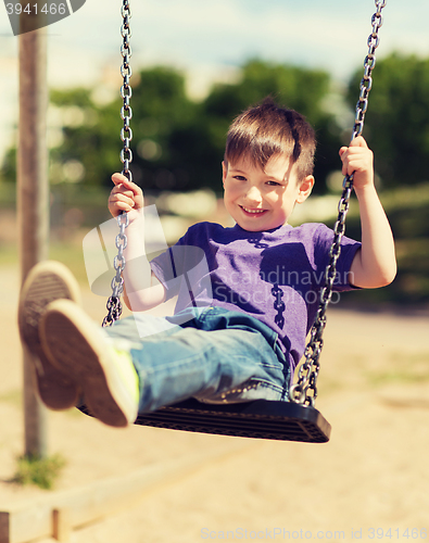 Image of happy little boy swinging on swing at playground