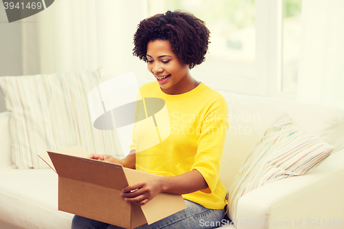 Image of happy african young woman with parcel box at home