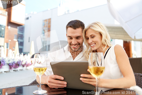 Image of happy couple with tablet pc at restaurant terrace