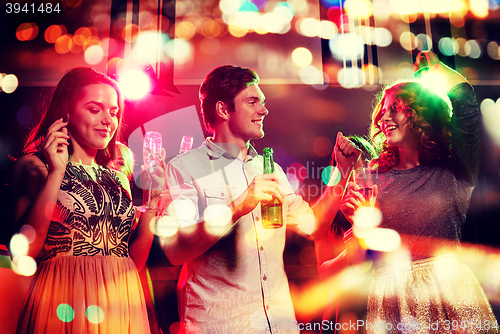 Image of smiling friends with wine glasses and beer in club