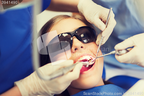 Image of female dentists treating patient girl teeth