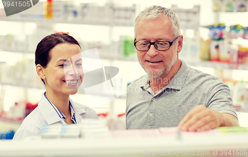 Image of pharmacist showing drug to senior man at pharmacy