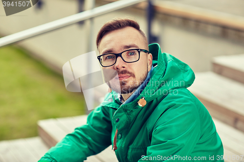 Image of happy young hipster man sitting on stairs in city