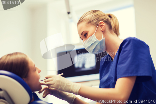 Image of female dentist checking patient girl teeth