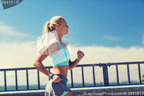 Image of smiling young woman running outdoors