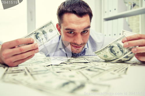 Image of happy businessman with heap of money in office