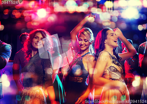 Image of happy friends dancing in club with holidays lights