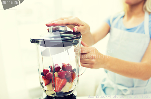 Image of close up of woman with blender making fruit shake