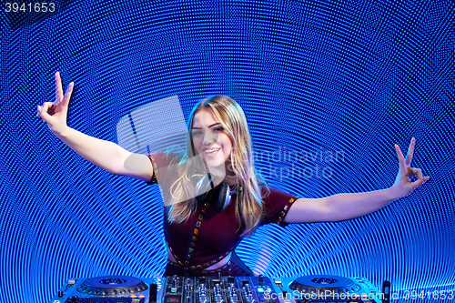 Image of DJ girl on decks at the party gesturing V sign
