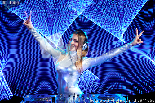 Image of DJ girl on decks at the party gesturing V sign