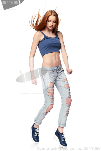 Image of Modern red haired girl in distressed jeans jumping posing