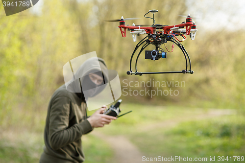 Image of Man in mask operating a drone with remote control.