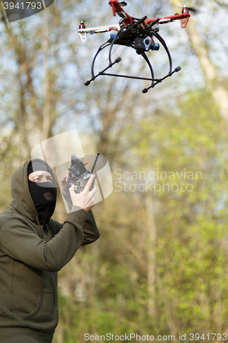 Image of Man in mask operating a drone with remote control.