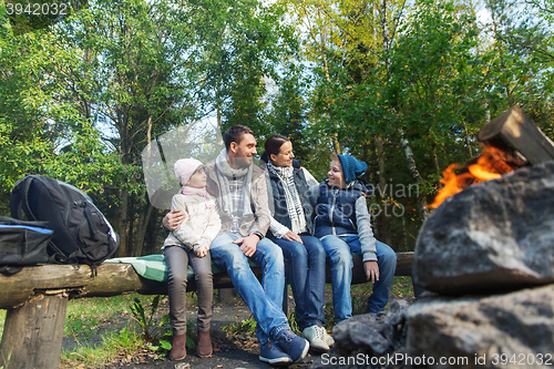 Image of happy family sitting on bench at camp fire