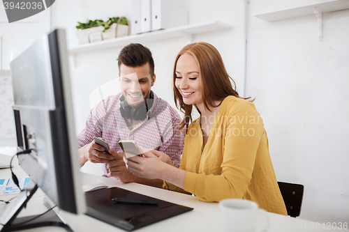 Image of happy creative team with smartphones at office