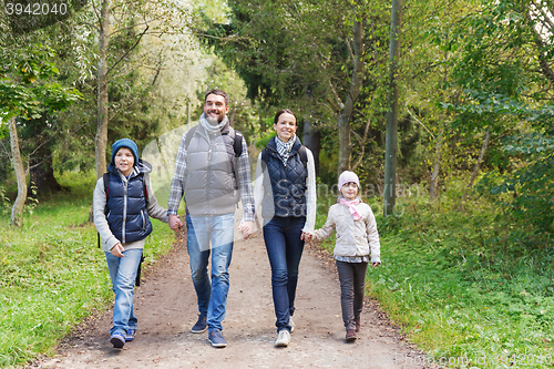 Image of happy family with backpacks hiking in woods