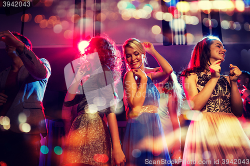 Image of happy friends dancing in club with holidays lights