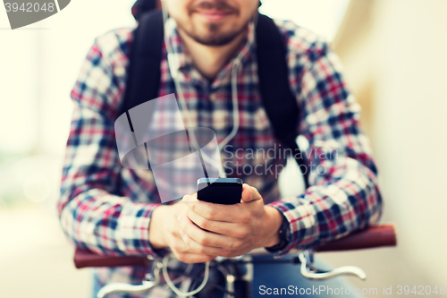 Image of hipster man in earphones with smartphone and bike