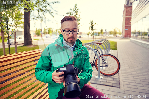 Image of young hipster man with digital camera in city