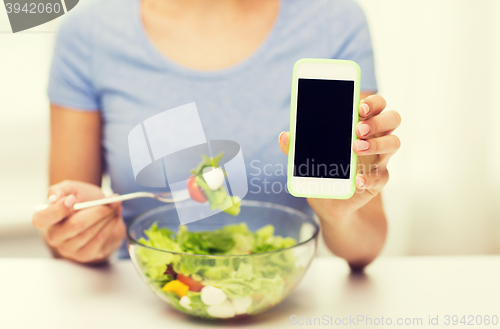 Image of close up of woman with smartphone eating salad