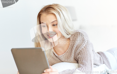 Image of happy young woman with tablet pc in bed at home