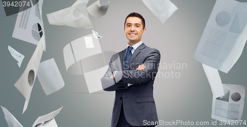 Image of happy smiling businessman in suit over papers