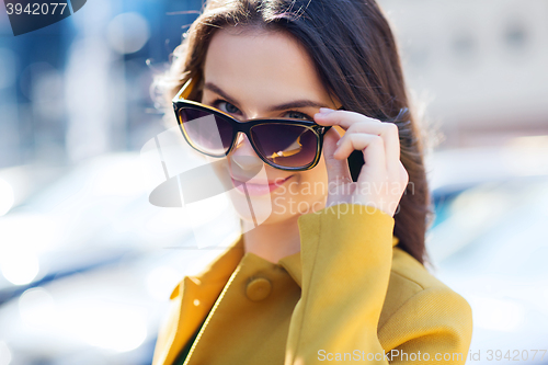 Image of smiling young woman with sunglasses in city