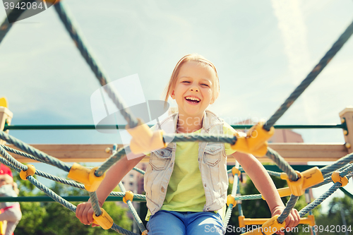 Image of happy little girl climbing on children playground