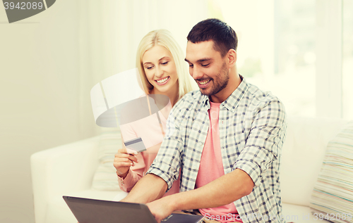 Image of happy couple with laptop and credit card at home