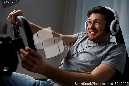 Image of man playing car racing video game at home