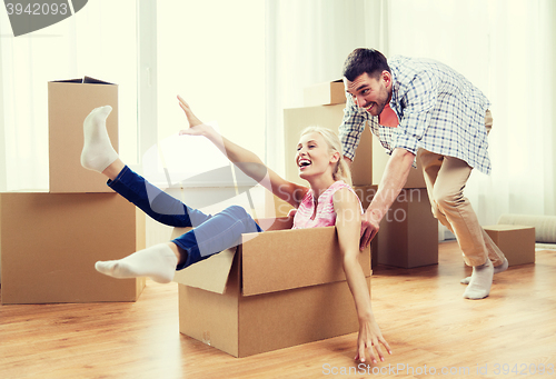 Image of couple with cardboard boxes having fun at new home