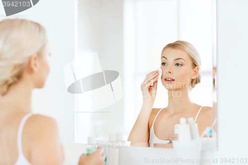 Image of young woman with lotion washing face at bathroom