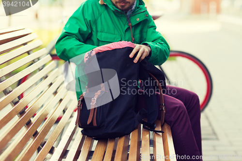 Image of close up of man with backpack on city bench