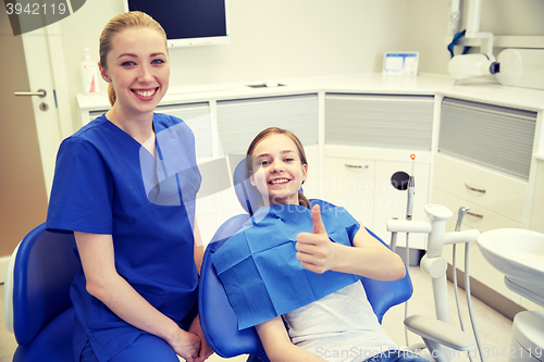 Image of happy female dentist with patient girl at clinic