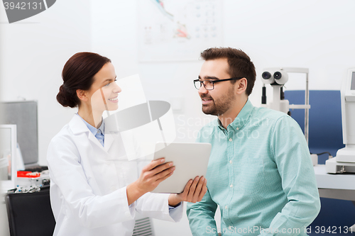 Image of optician with tablet pc and patient at eye clinic