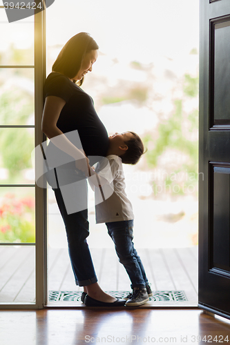 Image of Young Son Hugging Pregnant Mom in Doorway