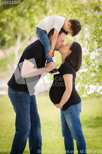 Image of Pregnant Mixed Race Couple Kissing with Young Son Riding Piggyba