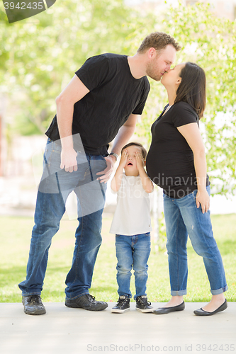 Image of Young Son Hides Eyes as Pregnant Mommy and Daddy Kiss