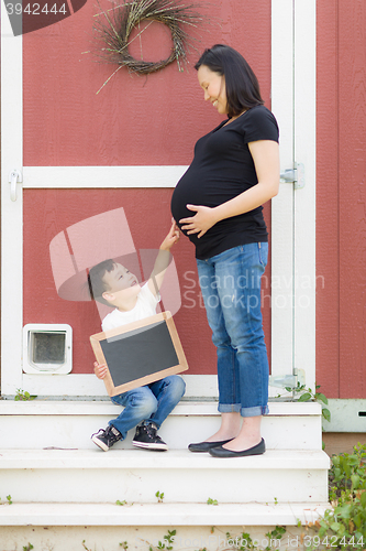 Image of Son with Blank Chalk Board Pointing to Pregnant Belly of Mommy