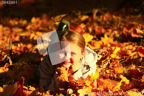 Image of little girl laying in yellow leaves