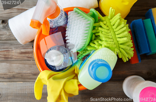 Image of Plastic bucket with cleaning supplies on wood background