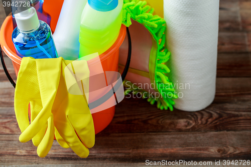 Image of Plastic bucket with cleaning supplies on wood background