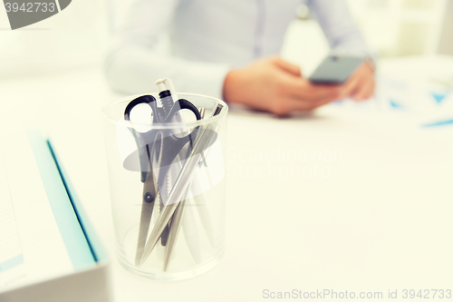 Image of close up of cup with scissors and pens at office