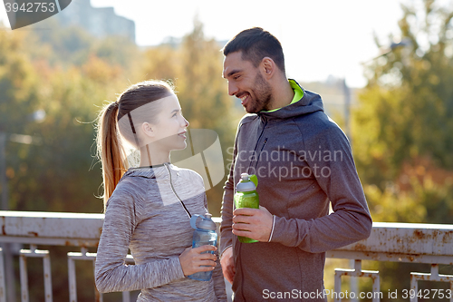 Image of smiling couple with bottles of water outdoors