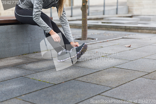 Image of close up of sporty woman tying shoes outdoors