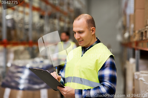 Image of man with clipboard in safety vest at warehouse